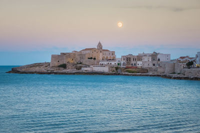 Pleasant view of vieste old town at dusk, church on the rocks in gargano, apulia, southern italy