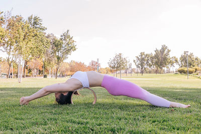 Fit young woman practicing yoga in the park. stretching on the wheel