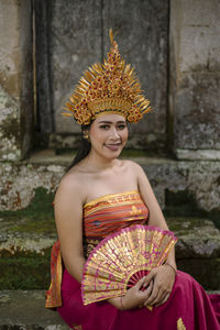 Portrait of young woman wearing traditional clothing sitting on steps against house