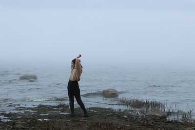 Rear view of man photographing sea against clear sky