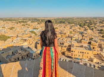 Rear view of woman looking at buildings against clear sky