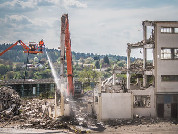 Construction site by abandoned building against sky