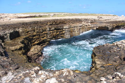 Scenic view of rocks on shore against sky