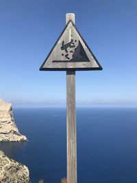 Low angle view of road sign against clear blue sky