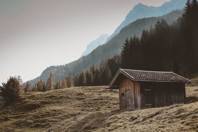 House amidst trees and mountains against sky