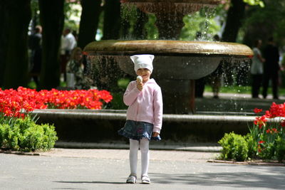 Portrait of girl standing by flowers