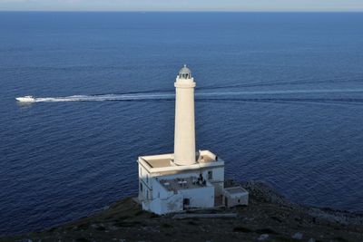 Lighthouse by sea against sky