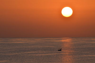 Lonely fishing boat passing the viewer while the sun is going down.