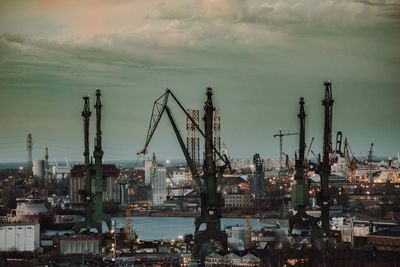 Cranes at harbor against sky