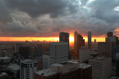 Modern buildings in city against sky during sunset