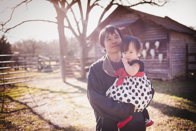 Man holding daughter on field during sunny day