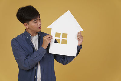 Full length of a man standing against yellow background