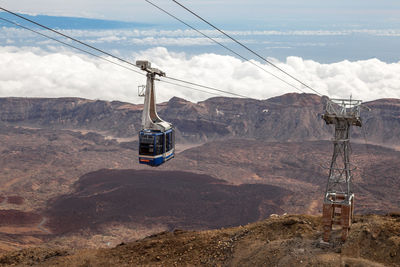 Overhead cable car over mountains against sky
