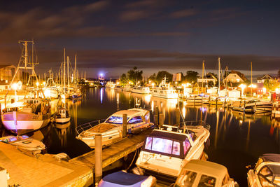 Boats moored at harbor against sky at night