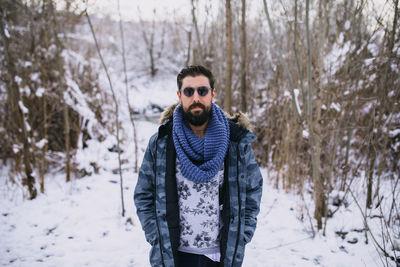 Portrait of young man standing on snow covered land