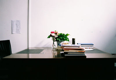 Flower vase on table against wall at home