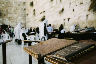 Torah on table with people standing by wailing wall