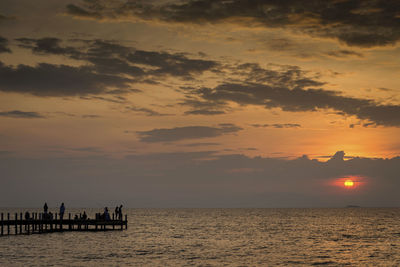 Silhouette people on beach against sky during sunset