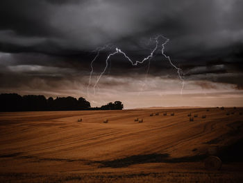 Scenic view of field against storm clouds