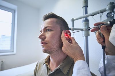 Cropped hand of doctor examining patients ear