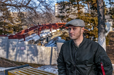 Portrait of young man standing against trees