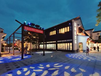 Information sign on illuminated building against sky at night