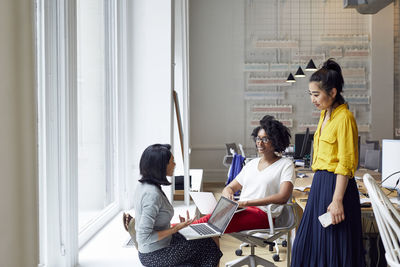 Businesswomen looking at female colleague talking in office