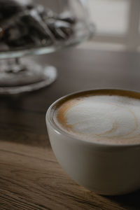 A cup of cappuccino close-up stands on the table, milk foam on the coffee drink