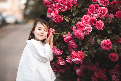 Beautiful cute kid girl 4-5 year old posing with pink roses outdoors closeup. summer season