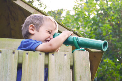 Boy looking through telescope in balcony