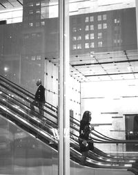 People on escalator seen through glass window