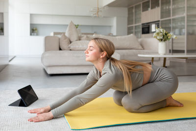 Young woman using mobile phone while sitting on sofa at home