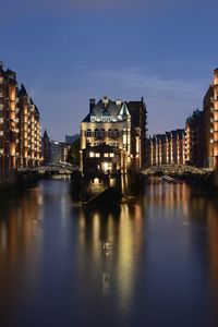 Illuminated buildings by river at night