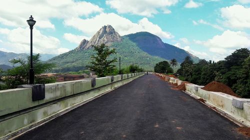 Road leading towards mountains against sky