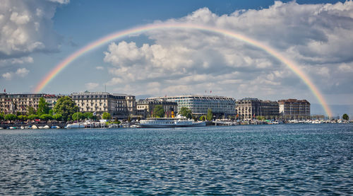 Scenic view of rainbow over sea against buildings in city