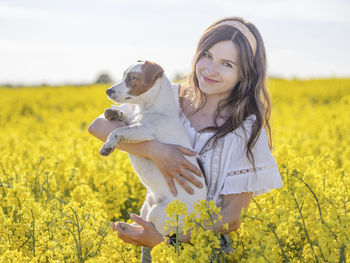 Beautiful woman with dog amidst yellow flowers on field