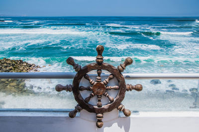 Close-up of wheel on beach against sky