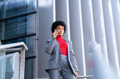 Young african american businesswoman in a suit in a corporate building holding the phone and laptop