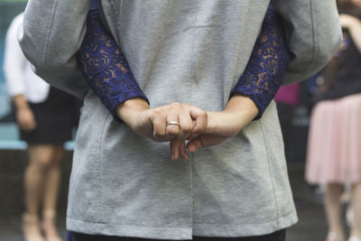 Midsection of couple holding hands standing outdoors