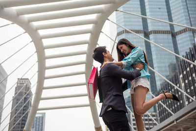 Low angle view of man and woman against built structure