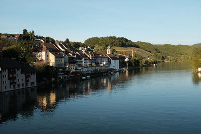 Buildings by river against clear sky