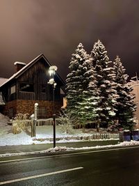 Snow covered road by building against sky at night