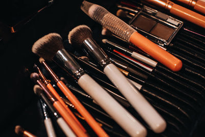 A set of different makeup artist brushes in a on black background