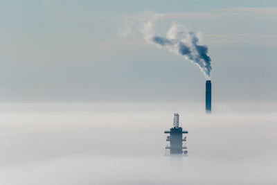 Smoke emitting from chimney against sky on a cold and foggy winter day