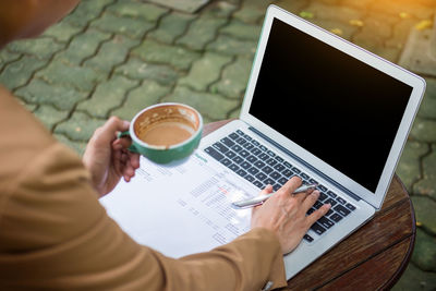Midsection of woman using laptop on table