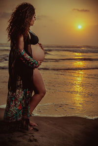 Woman standing at beach during sunset