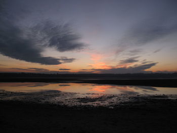 Scenic view of beach against dramatic sky