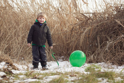 Portrait of boy with helium balloon standing on snow