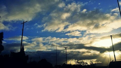 Low angle view of power lines against cloudy sky