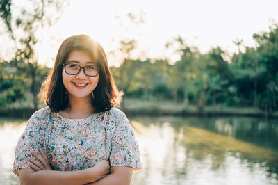 Portrait of smiling young woman against lake